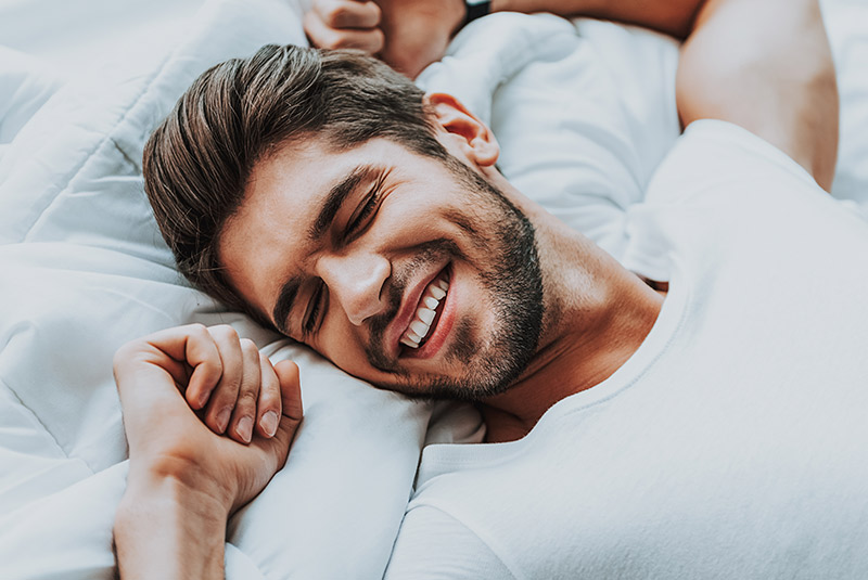 Very nice guy smiling in bed happy because he went to Wellington Family Dentistry & Implant Center to treat his sleep apnea