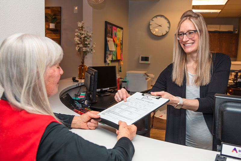 Patient getting help from the front desk with onboarding dental process